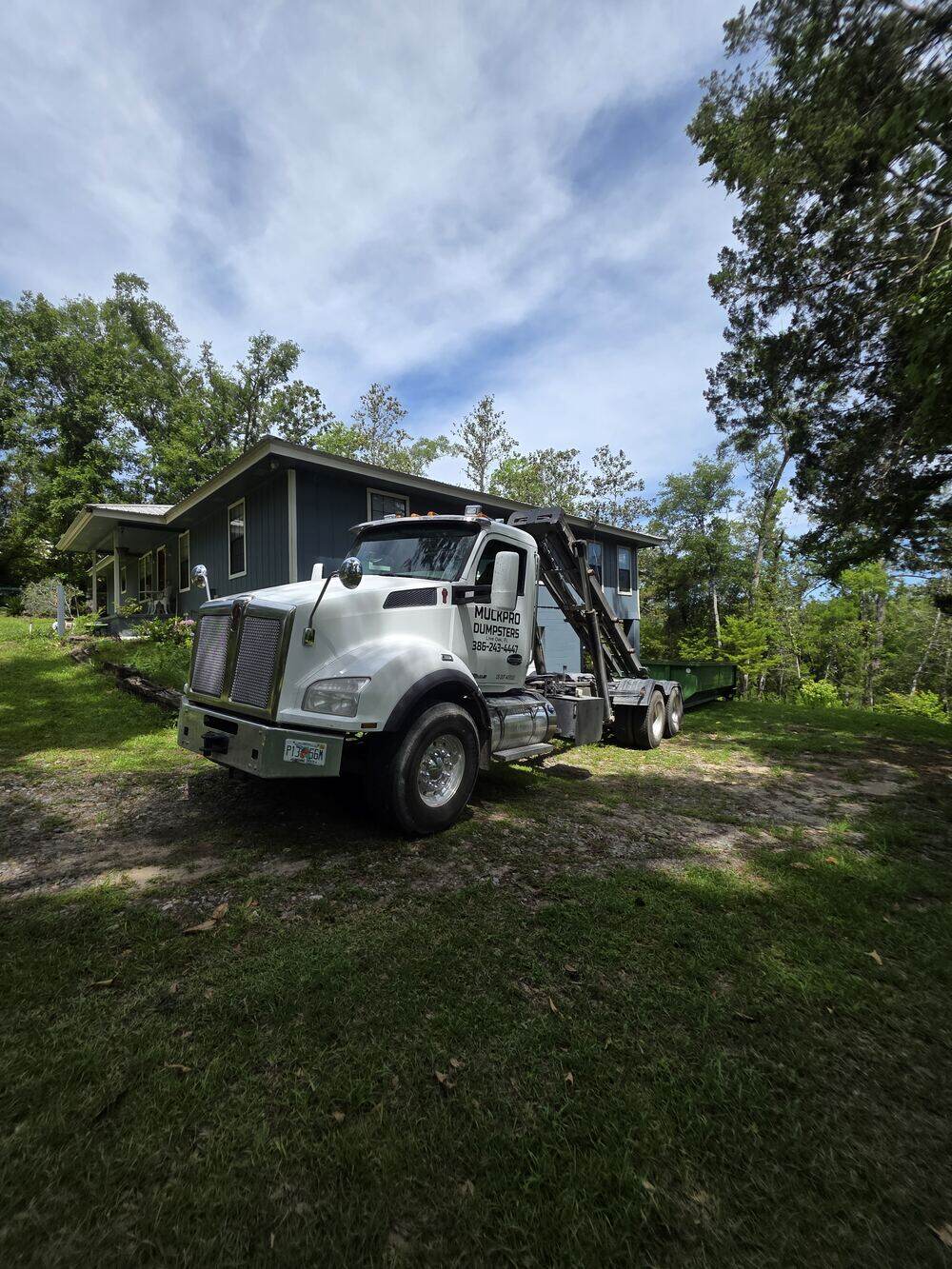 Muckpro roll-off truck delivering a dumpster to a Live Oak home